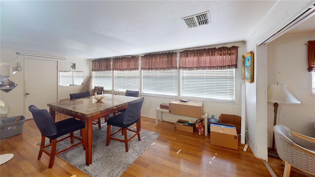A dining room features a marble-topped table, dark chairs, wood flooring, and large windows — 1721 W NORTH B STREET, TAMPA, FL