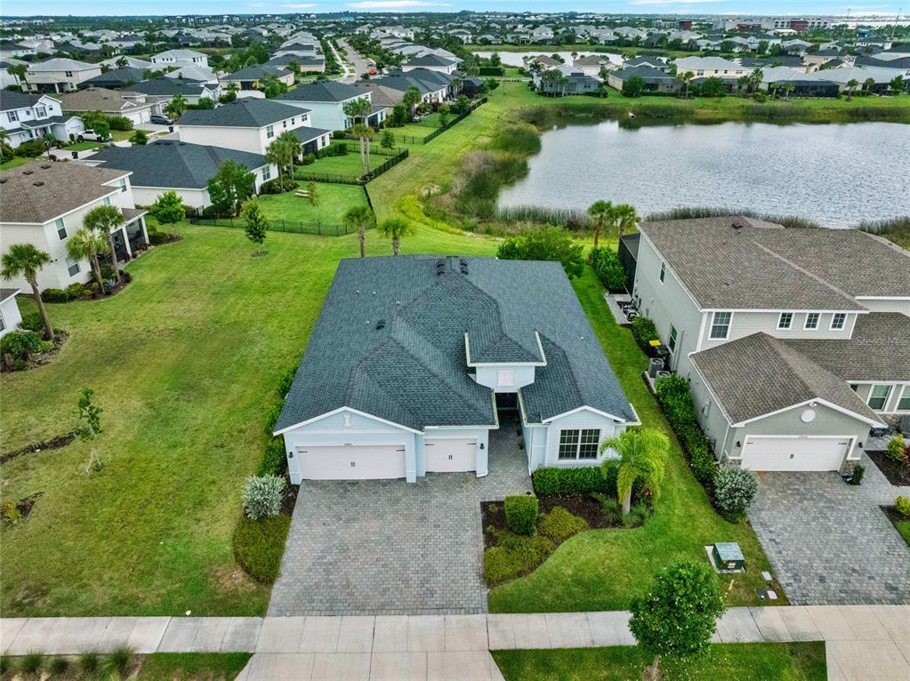 An aerial view shows a single-story house with a paver driveway and a backyard pond — 17661 FALLEN BRANCH WAY, PUNTA GORDA, FL