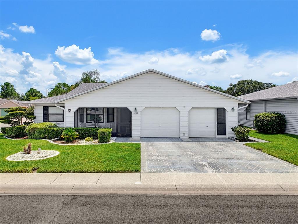A single-story white house features a two-car garage, a screened porch, and a paved driveway — 1804 MASTERS LANE, LAKELAND, FL