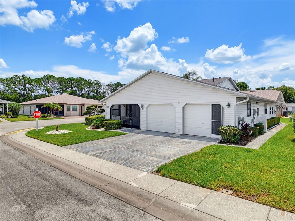 A white duplex home features two garage doors, a paved driveway, and a corner lot — 1804 MASTERS LANE, LAKELAND, FL