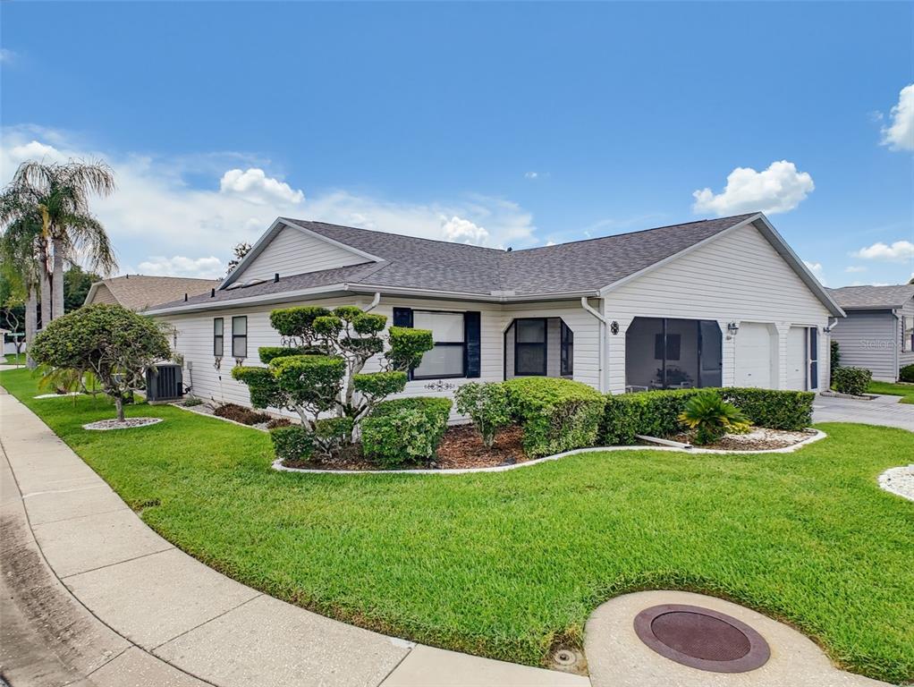 A single-story house with white siding, a shingled roof, and manicured landscaping — 1804 MASTERS LANE, LAKELAND, FL
