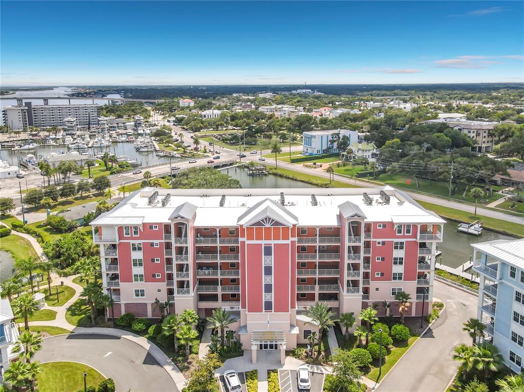 An aerial view shows a multi-story pink residential building with a white roof and balconies — 2 RIVERWALK DRIVE UNIT 404, NEW SMYRNA BEACH, FL