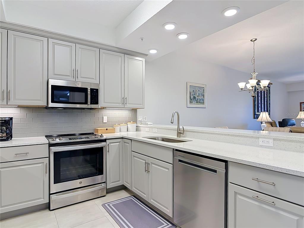 A kitchen features light gray cabinets, stainless steel appliances, and white quartz countertops — 2 RIVERWALK DRIVE UNIT 404, NEW SMYRNA BEACH, FL