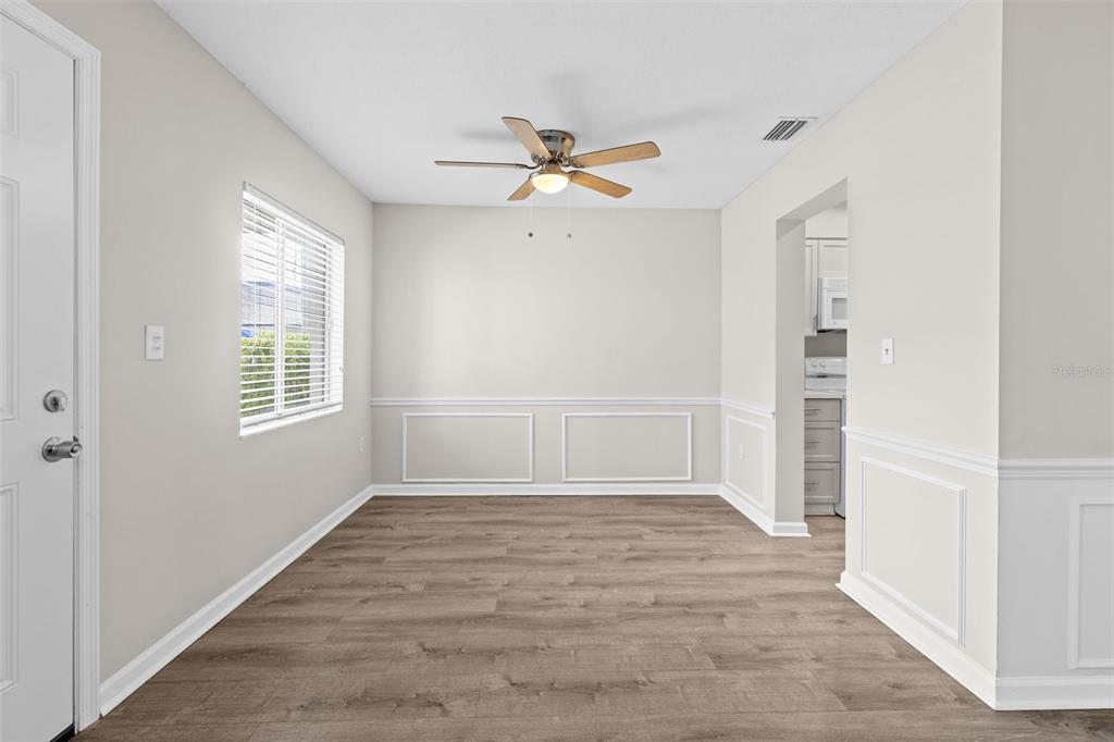 A dining room with light-colored walls, wood-look flooring, a ceiling fan, and white wainscoting — 350 79TH AVENUE N UNIT 134, ST PETERSBURG, FL