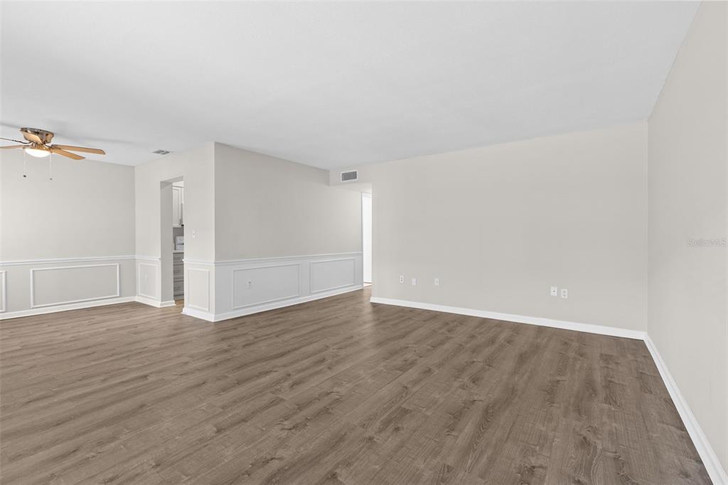 An empty room with light-colored walls, white wainscoting, and wood-look flooring — 350 79TH AVENUE N UNIT 134, ST PETERSBURG, FL
