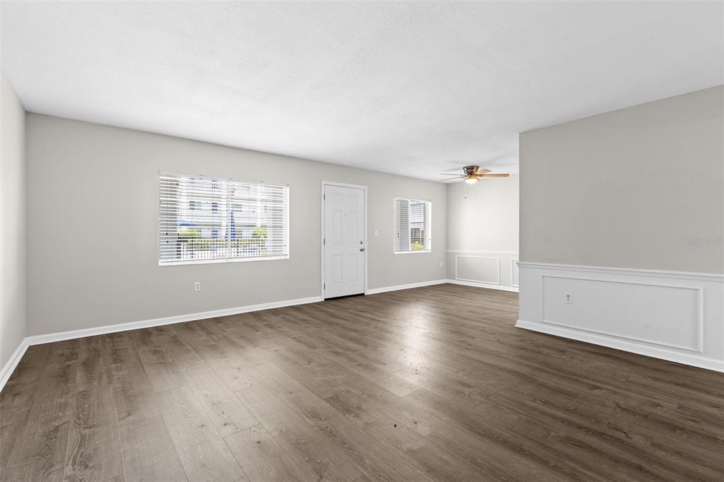 An empty living room features light gray walls, wood-look flooring, and a white front door — 350 79TH AVENUE N UNIT 134, ST PETERSBURG, FL
