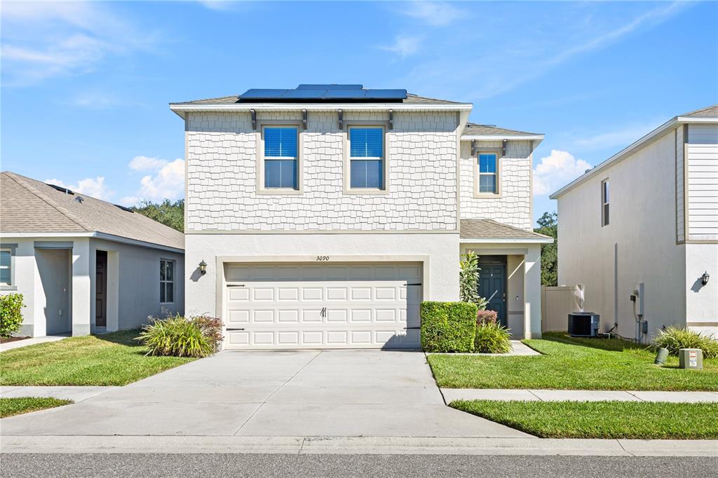 A two-story house with a beige stucco and shingle exterior, a garage, and a driveway — 3090 TIMBER HAWK CIRCLE, OCOEE, FL