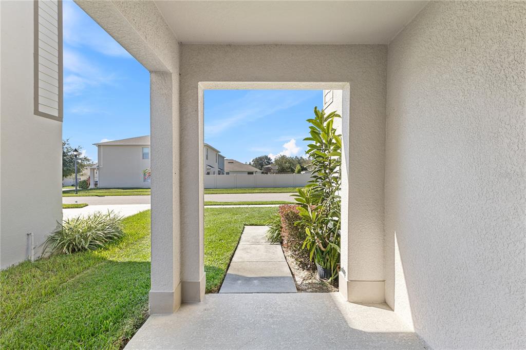 A view from a covered entryway looking out toward a sidewalk and residential neighborhood — 3090 TIMBER HAWK CIRCLE, OCOEE, FL