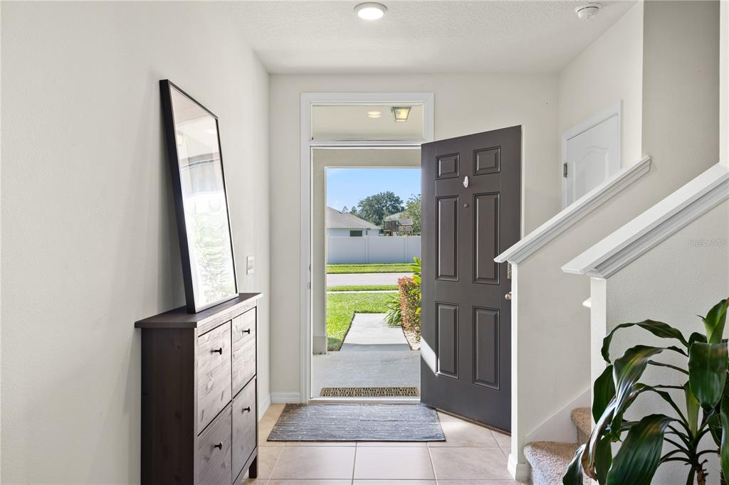 An entryway features a dark wooden cabinet, a staircase, and an open door to outside — 3090 TIMBER HAWK CIRCLE, OCOEE, FL