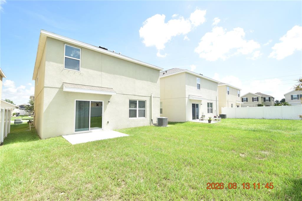 The rear exterior of a two-story house features a sliding glass door and concrete patio — 10233 MANGROVE WELL ROAD, SUN CITY CENTER, FL