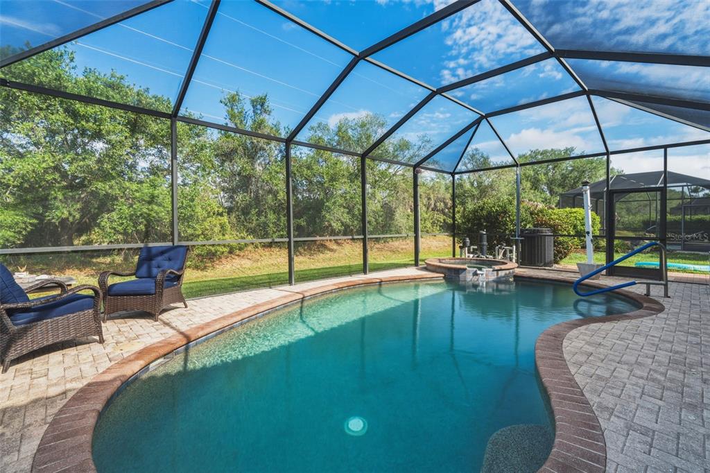 A screened-in swimming pool and hot tub on a paved patio with outdoor seating — 1934 MESIC HAMMOCK WAY, VENICE, FL