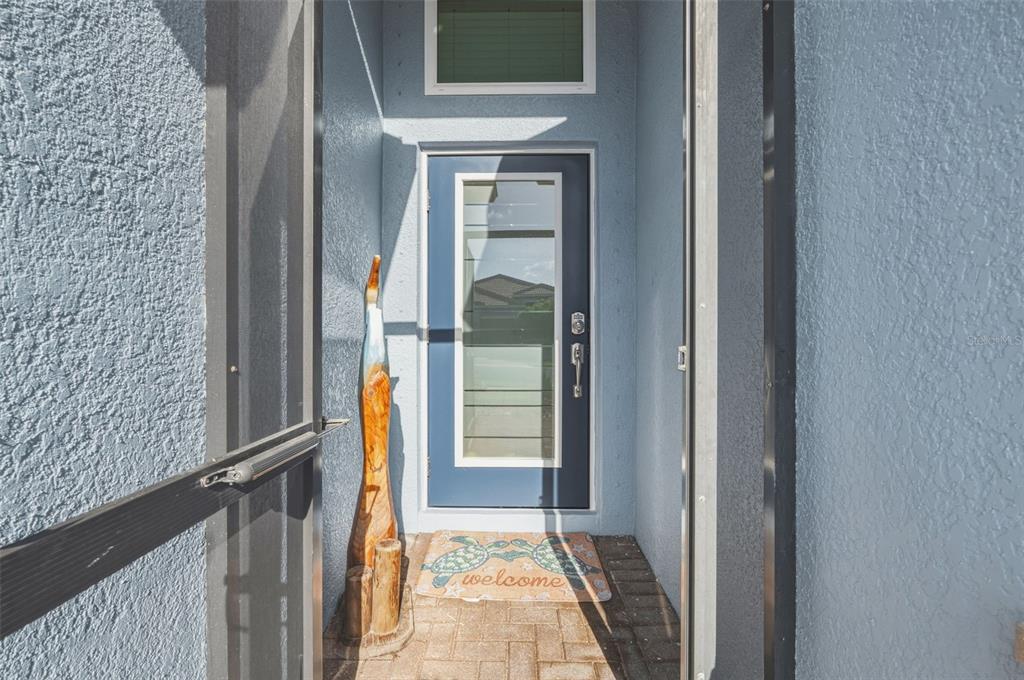 A blue front door with a glass insert sits within a covered entryway — 1934 MESIC HAMMOCK WAY, VENICE, FL