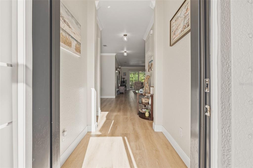 A view from an entryway looking down a hallway with light wood-look flooring — 1934 MESIC HAMMOCK WAY, VENICE, FL