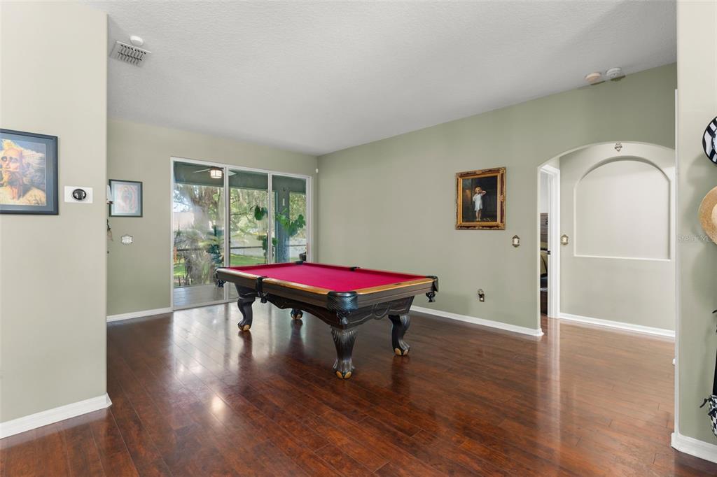 A room with dark wood flooring features a pool table and a sliding glass door — 428 SHADY PINE COURT, MINNEOLA, FL