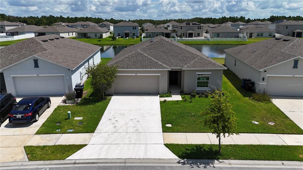 An aerial view of a suburban house with a concrete driveway and a backyard pond — 486 PINE TREE BRIDGE TRAIL, ST CLOUD, FL