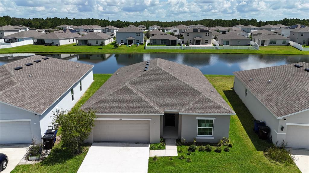 An aerial view of a suburban house with a gray roof and a backyard pond — 486 PINE TREE BRIDGE TRAIL, ST CLOUD, FL