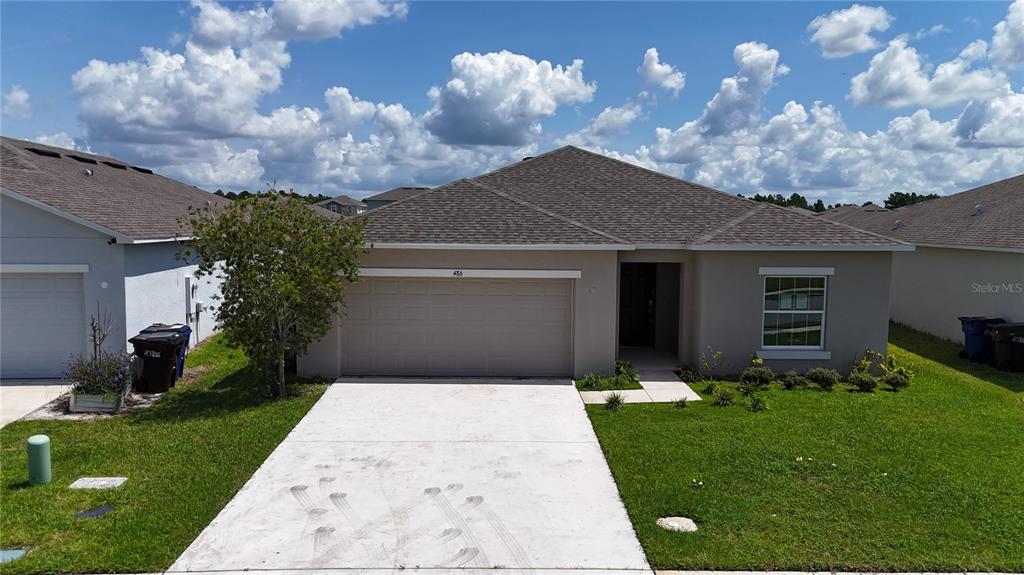 A single-story suburban house features a two-car garage, a concrete driveway, and a grassy lawn — 486 PINE TREE BRIDGE TRAIL, ST CLOUD, FL