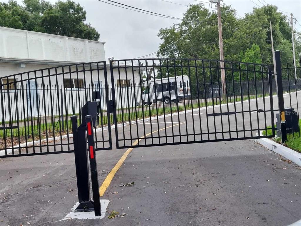 A black metal security gate stands across a paved driveway in front of a building — 1776 6TH STREET NW UNIT 308, WINTER HAVEN, FL