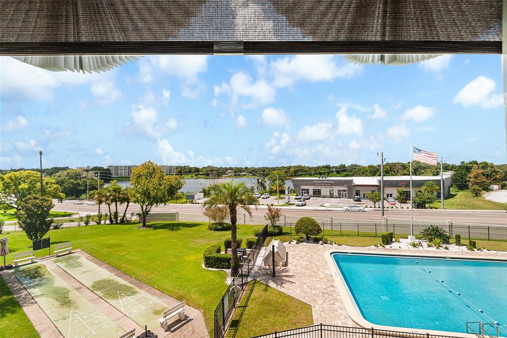 An elevated view shows a swimming pool, shuffleboard courts, and a nearby commercial building — 1776 6TH STREET NW UNIT 308, WINTER HAVEN, FL