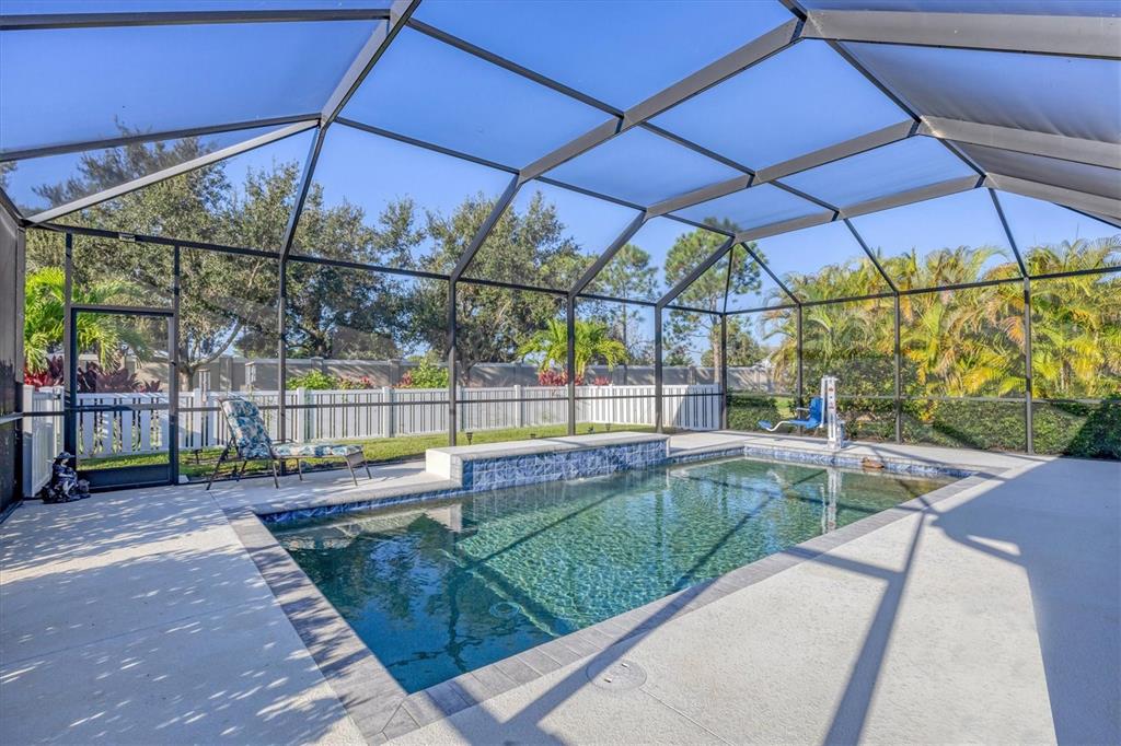 The exterior of a single-story house features a garage, a covered porch, and landscaping — 7040 WHITE WILLOW COURT, SARASOTA, FL