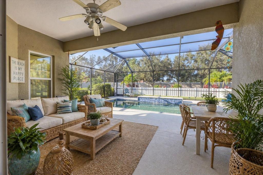 A covered front porch features two wooden rocking chairs, white railings, and square support columns — 7040 WHITE WILLOW COURT, SARASOTA, FL