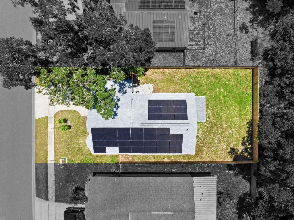 An aerial view shows a gray house with solar panels on its roof and a fenced yard — 6330 RUTHIE DRIVE, ORLANDO, FL