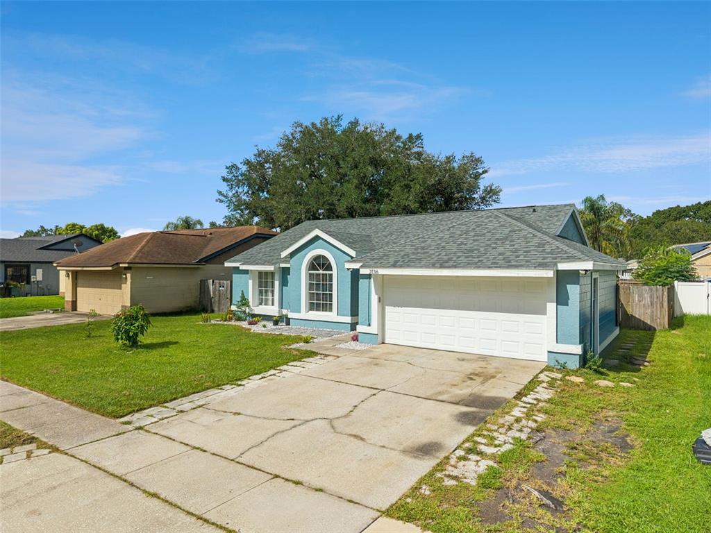 A single-story house with blue siding, a white garage door, and a concrete driveway — 2136 OPAL DRIVE, ORLANDO, FL