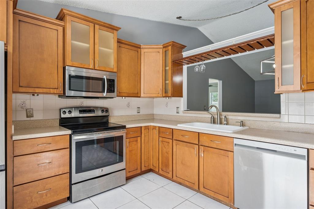A kitchen with wood cabinets, stainless steel appliances, a white sink, and tiled countertops — 2136 OPAL DRIVE, ORLANDO, FL