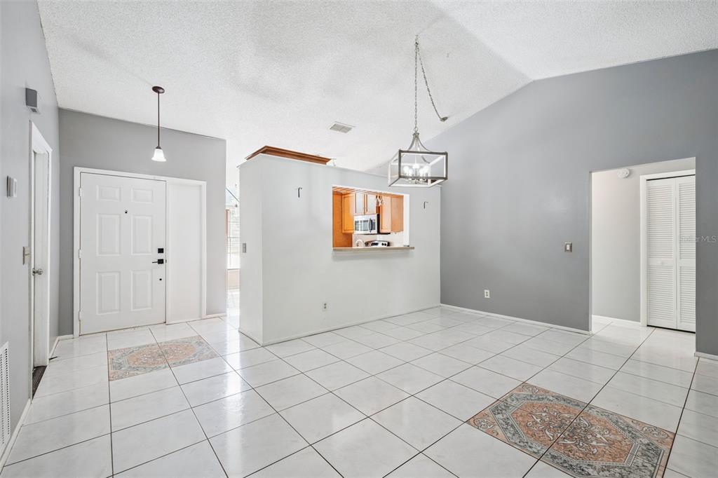 A bright dining area features white tile flooring, a vaulted ceiling, and a kitchen pass-through window — 2136 OPAL DRIVE, ORLANDO, FL