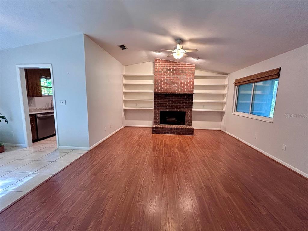 A living room features wood-look flooring, a brick fireplace, and built-in shelving — 4135 NW 30TH TERRACE, GAINESVILLE, FL