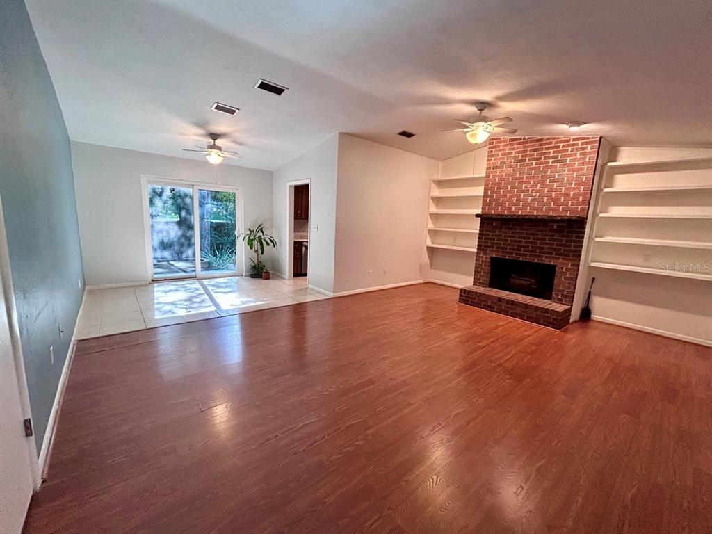 A living room features wood flooring, a brick fireplace, built-in shelves, and sliding glass doors — 4135 NW 30TH TERRACE, GAINESVILLE, FL