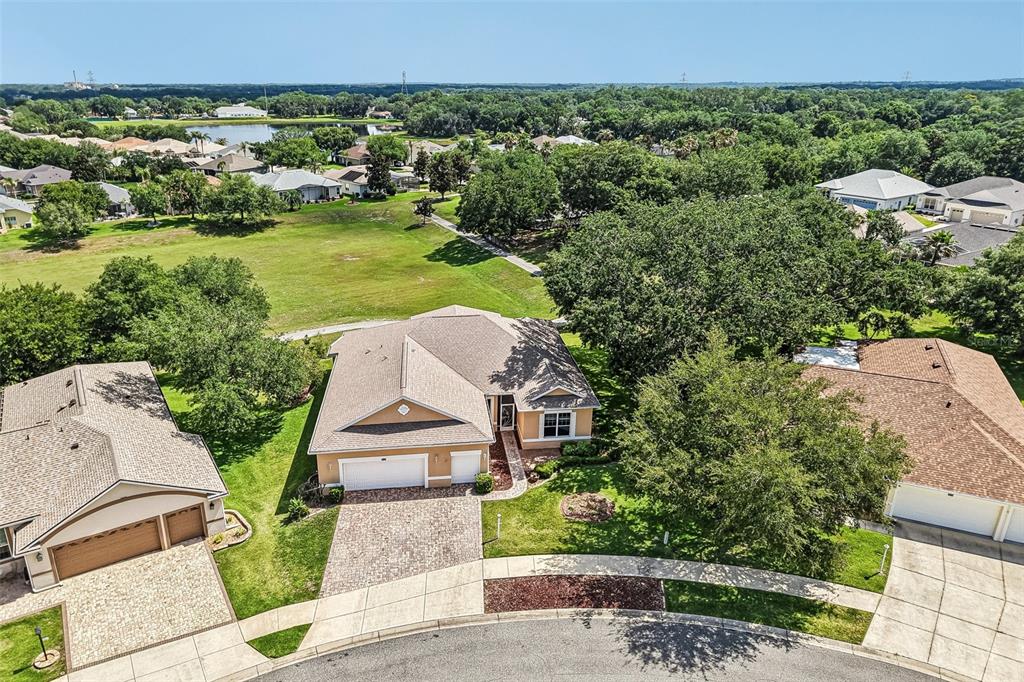 A single-story house with a tan stucco exterior, a three-car garage, and a paved driveway — 3538 MULBERRY GROVE LOOP, LEESBURG, FL