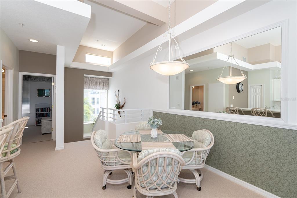 A dining area with a glass table, wicker chairs, and a large wall mirror — 8280 HARBORSIDE CIRCLE, ENGLEWOOD, FL