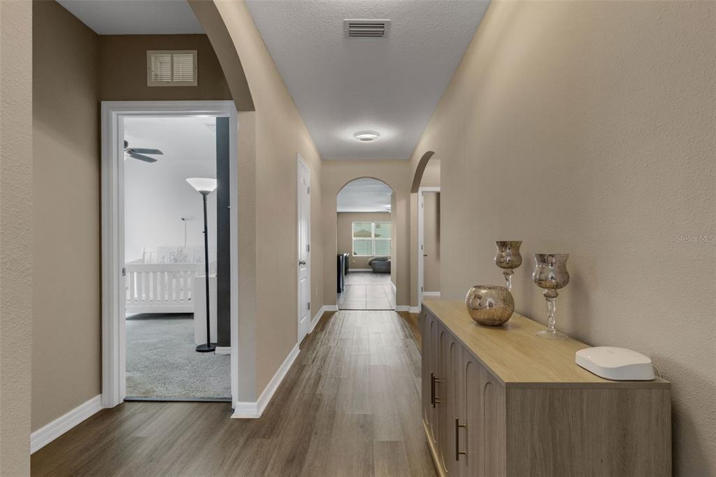 A hallway with wood-look flooring leads to an arched doorway and a room beyond — 15215 PEACEFUL BULL PLACE, BRADENTON, FL