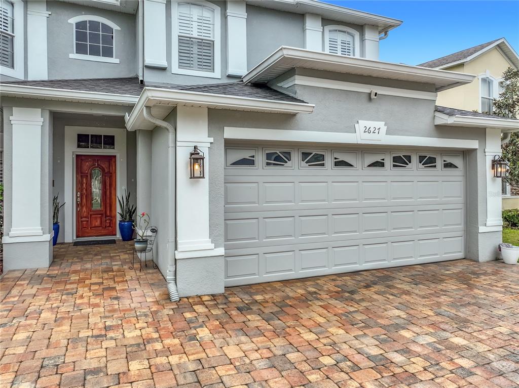 A two-story house exterior features a gray stucco facade, a garage, and a paver driveway — 2627 LAKEMOOR DRIVE, ORLANDO, FL