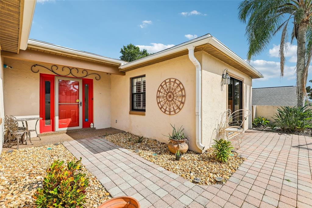 The exterior of a house features a red front door, a paver walkway, and landscaping — 1665 GOLFSIDE VILLAGE BOULEVARD, APOPKA, FL