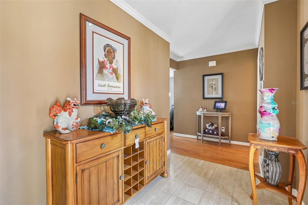 A hallway with tile flooring, a wooden wine cabinet, and a decorative vase on a stand — 1665 GOLFSIDE VILLAGE BOULEVARD, APOPKA, FL
