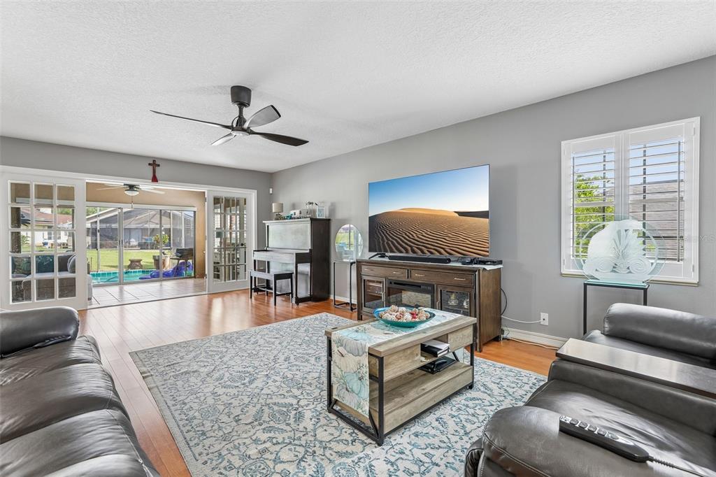 A living room features leather sofas, a television on a console, and a sliding glass door — 1665 GOLFSIDE VILLAGE BOULEVARD, APOPKA, FL