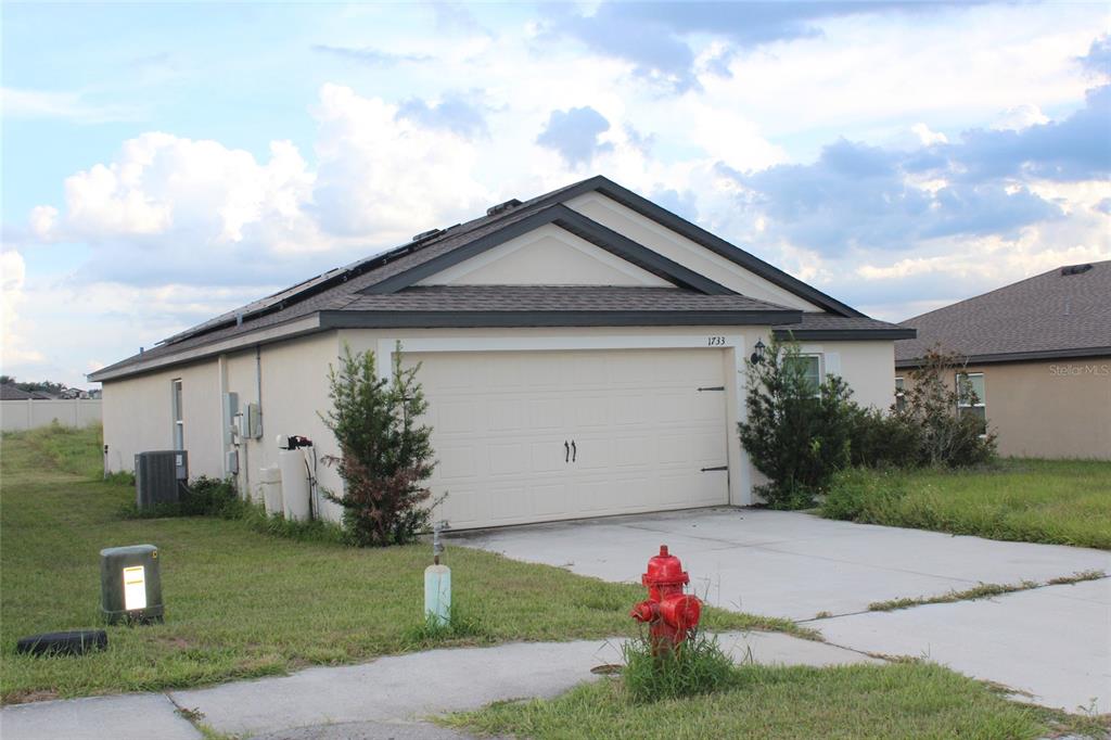 A single-story house with a beige exterior, a two-car garage, and a red fire hydrant — 1733 CANAAN LOOP, DUNDEE, FL