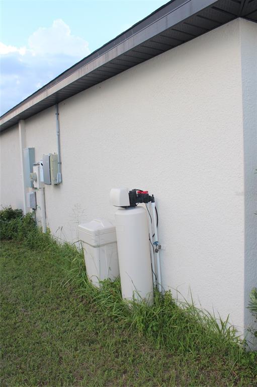 An exterior view of a house wall featuring electrical boxes and a water softener system — 1733 CANAAN LOOP, DUNDEE, FL