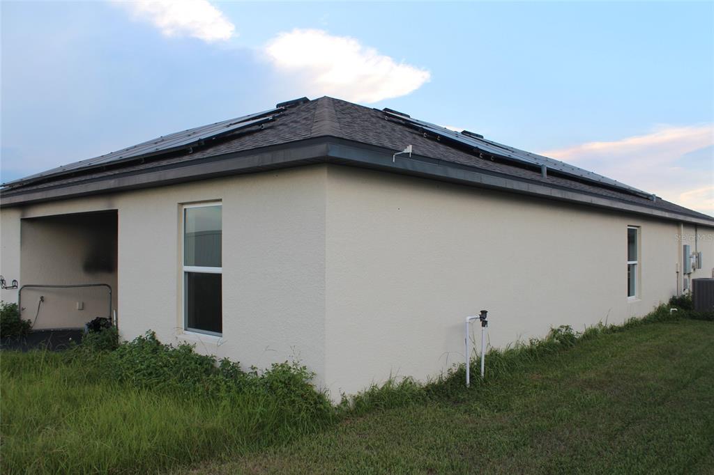 A side view of a beige stucco house with solar panels on the roof — 1733 CANAAN LOOP, DUNDEE, FL