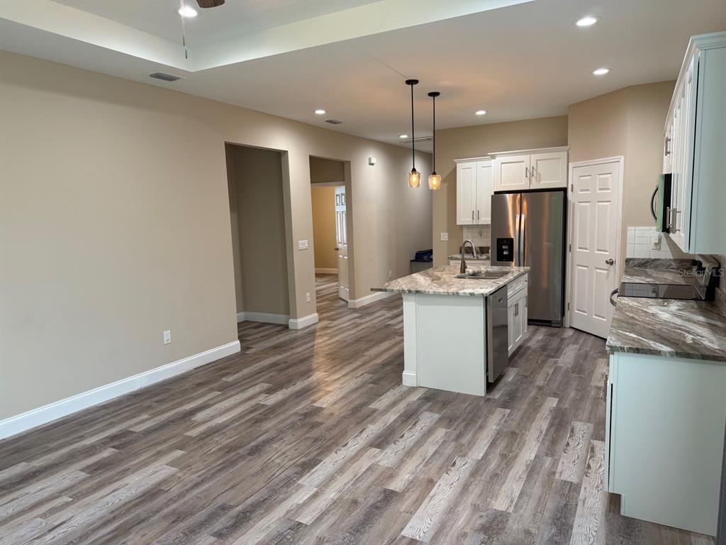 A kitchen with a marble-topped island, stainless steel appliances, and light-colored wood-look flooring — 540 LINDSAY ANNE COURT, PLANT CITY, FL