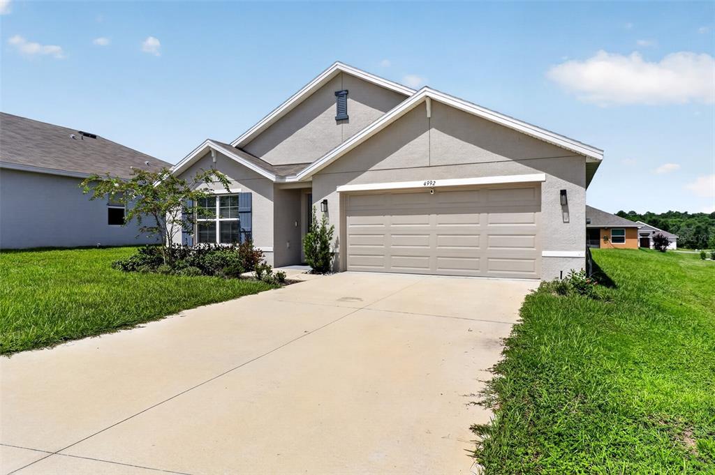 A single-story house with a beige stucco exterior, a two-car garage, and a concrete driveway — 4992 N FAIRWAYS RIDGE POINT, BEVERLY HILLS, FL