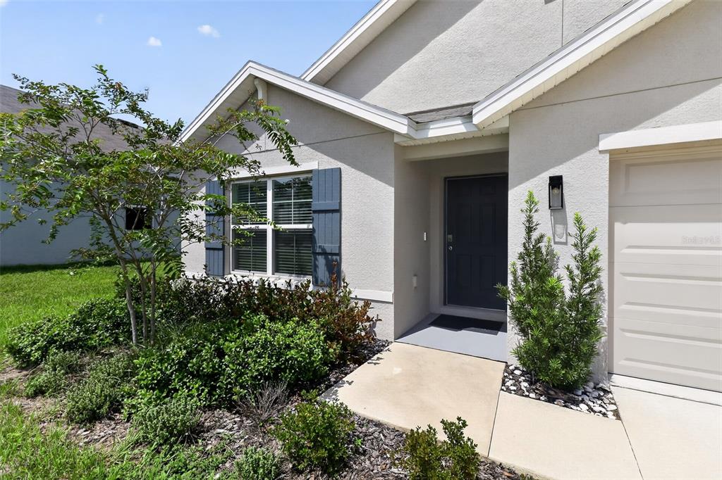 A beige house exterior features a dark front door, blue shutters, and a small garden — 4992 N FAIRWAYS RIDGE POINT, BEVERLY HILLS, FL