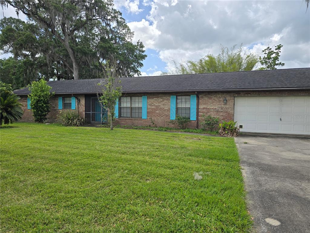 A single-story brick house features a white garage door, blue shutters, and a front lawn — 4506 SE 7TH PLACE, OCALA, FL