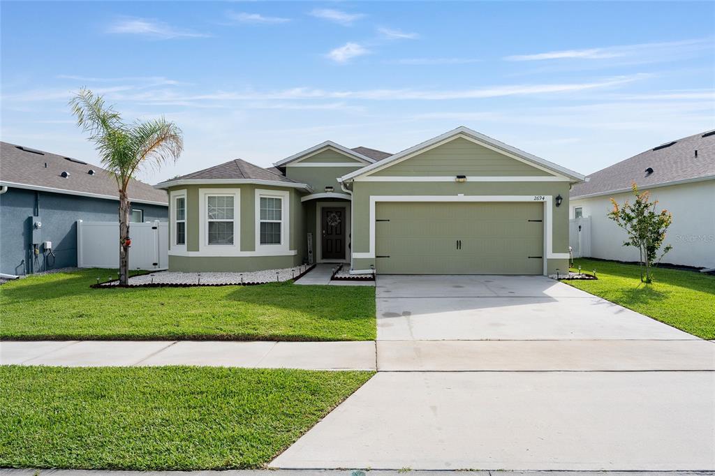 A single-story house with light green siding, a two-car garage, and a front lawn — 2694 NEVERLAND DRIVE, NEW SMYRNA BEACH, FL