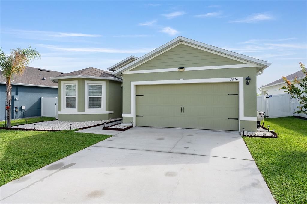 A light green single-story house features a two-car garage and a concrete driveway — 2694 NEVERLAND DRIVE, NEW SMYRNA BEACH, FL