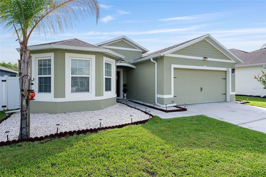 A single-story house with green siding, a two-car garage, and a white gravel front yard — 2694 NEVERLAND DRIVE, NEW SMYRNA BEACH, FL