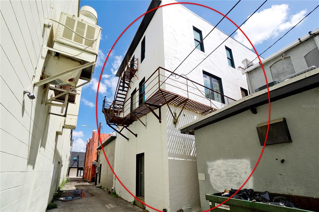 A white brick building exterior features a metal fire escape and balcony in an alleyway — 420 12TH STREET W, BRADENTON, FL