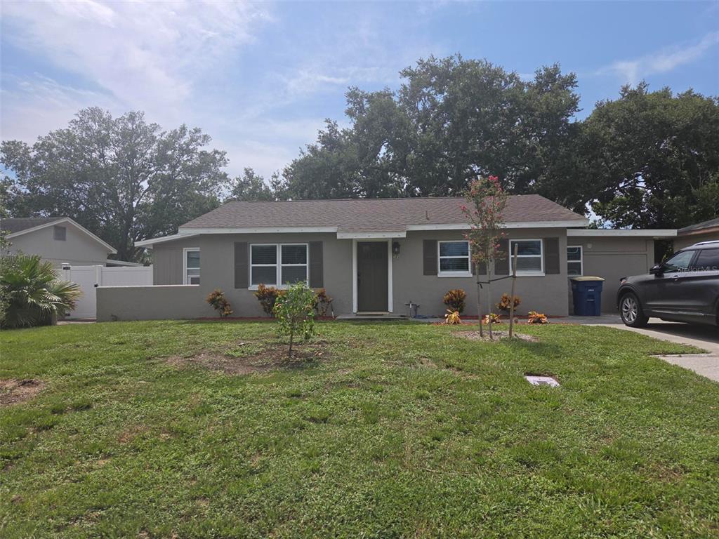 A single-story gray house with a brown roof, a front lawn, and a driveway — 20 S SATURN AVENUE, CLEARWATER, FL